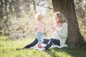 une mère adossée à un arbre avec son enfant dans la nature
